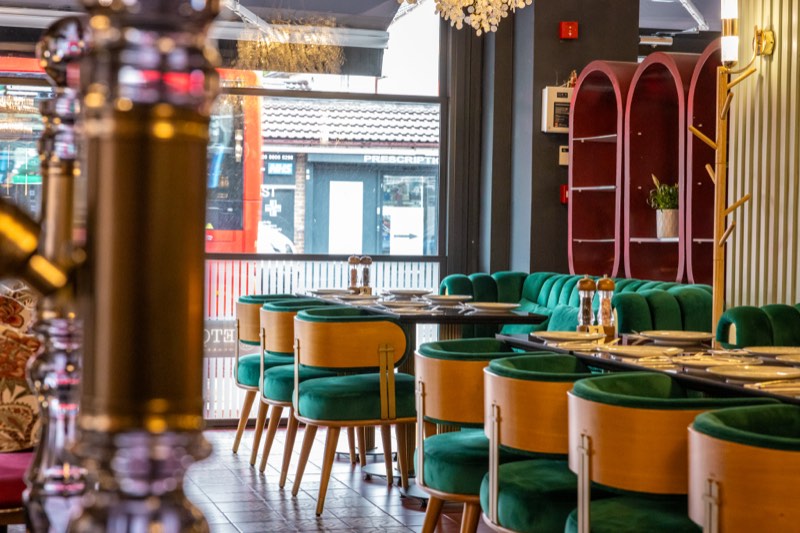 Green-velvet seating in the daylit dining room